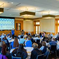 Overview photo of Alumni sitting at tables, listening to T-Haas speak